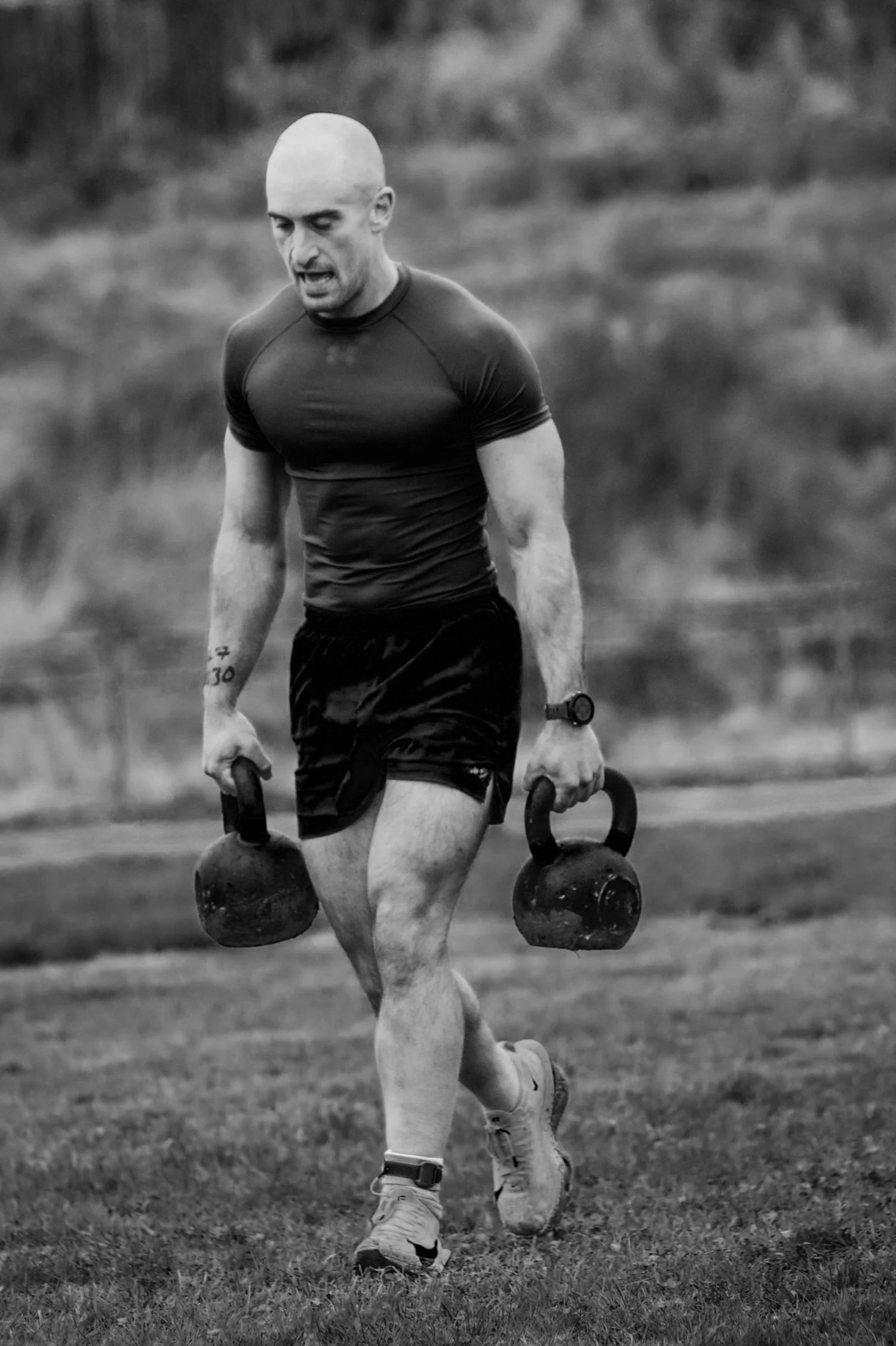 Atlet membawa dua kettlebell di lorong 30m dalam acara Farmers Carry Labour